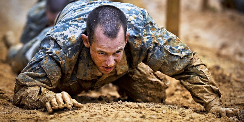 Military soldier crawling through mud