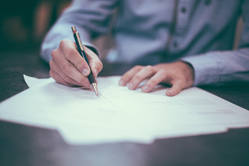Close up picture of a person's hands signing a document